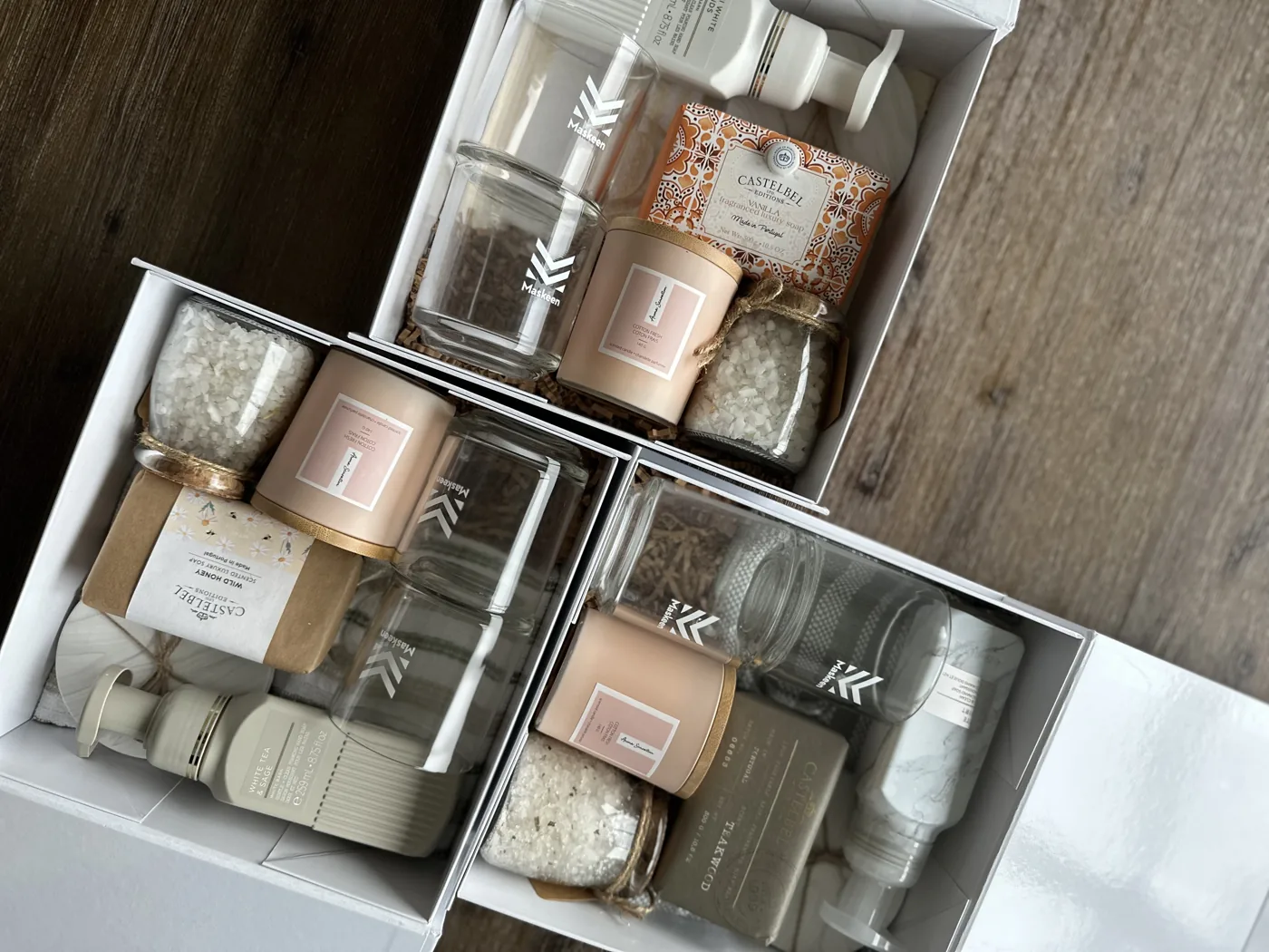 Three white corporate gift boxes with branded glass jars, candles and soaps